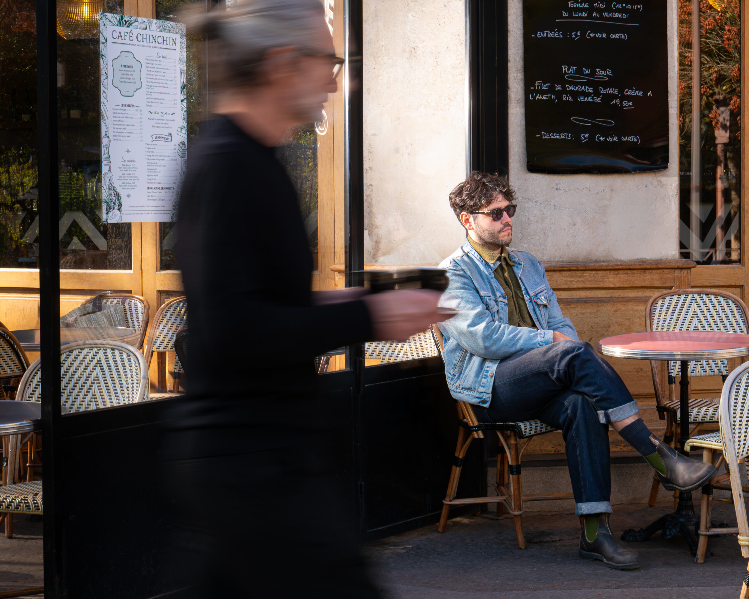 Homme en terrasse d'un café parisien avec le serveur en action