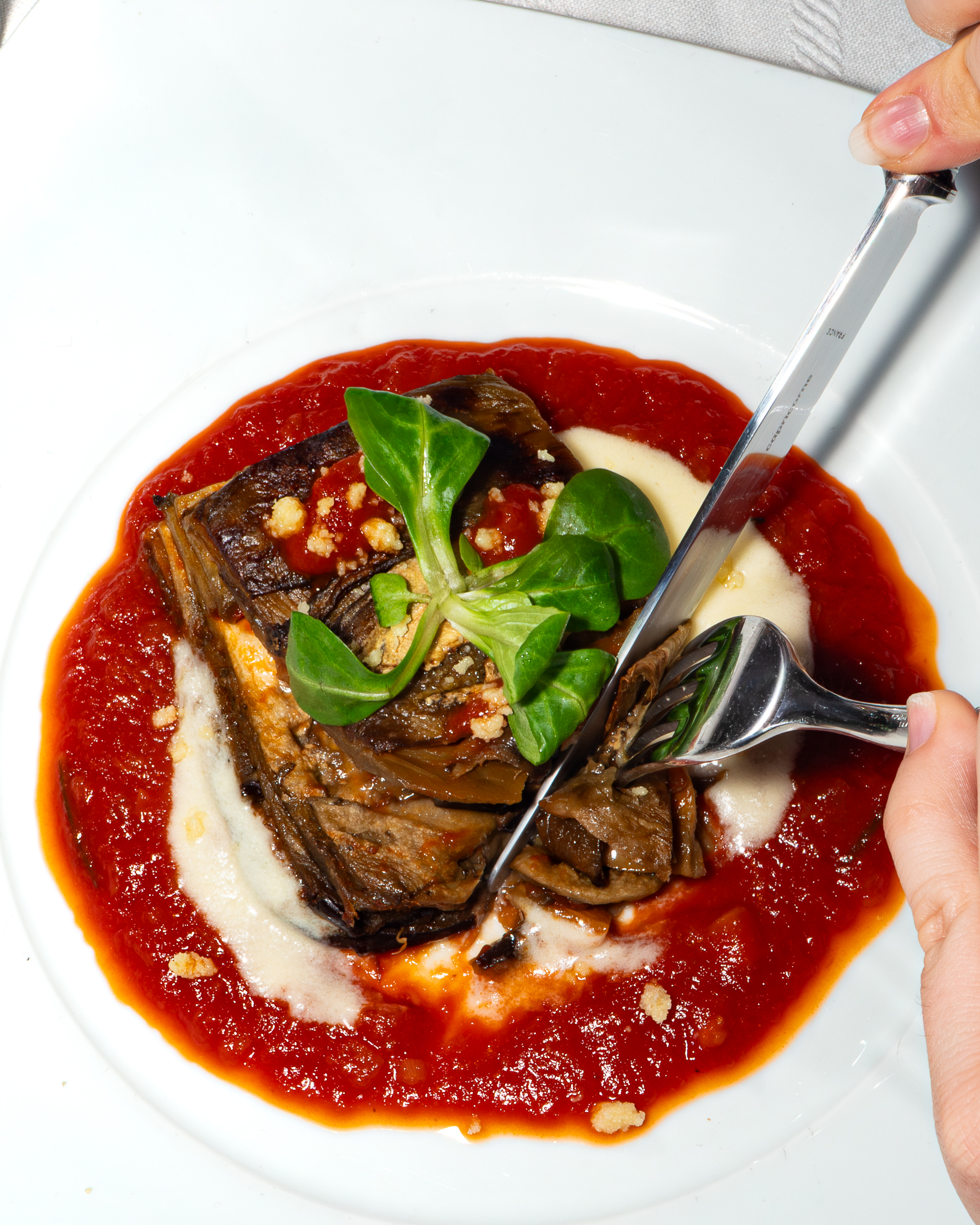Table de restaurant jeune femme en train de couper une part de parmigiana 