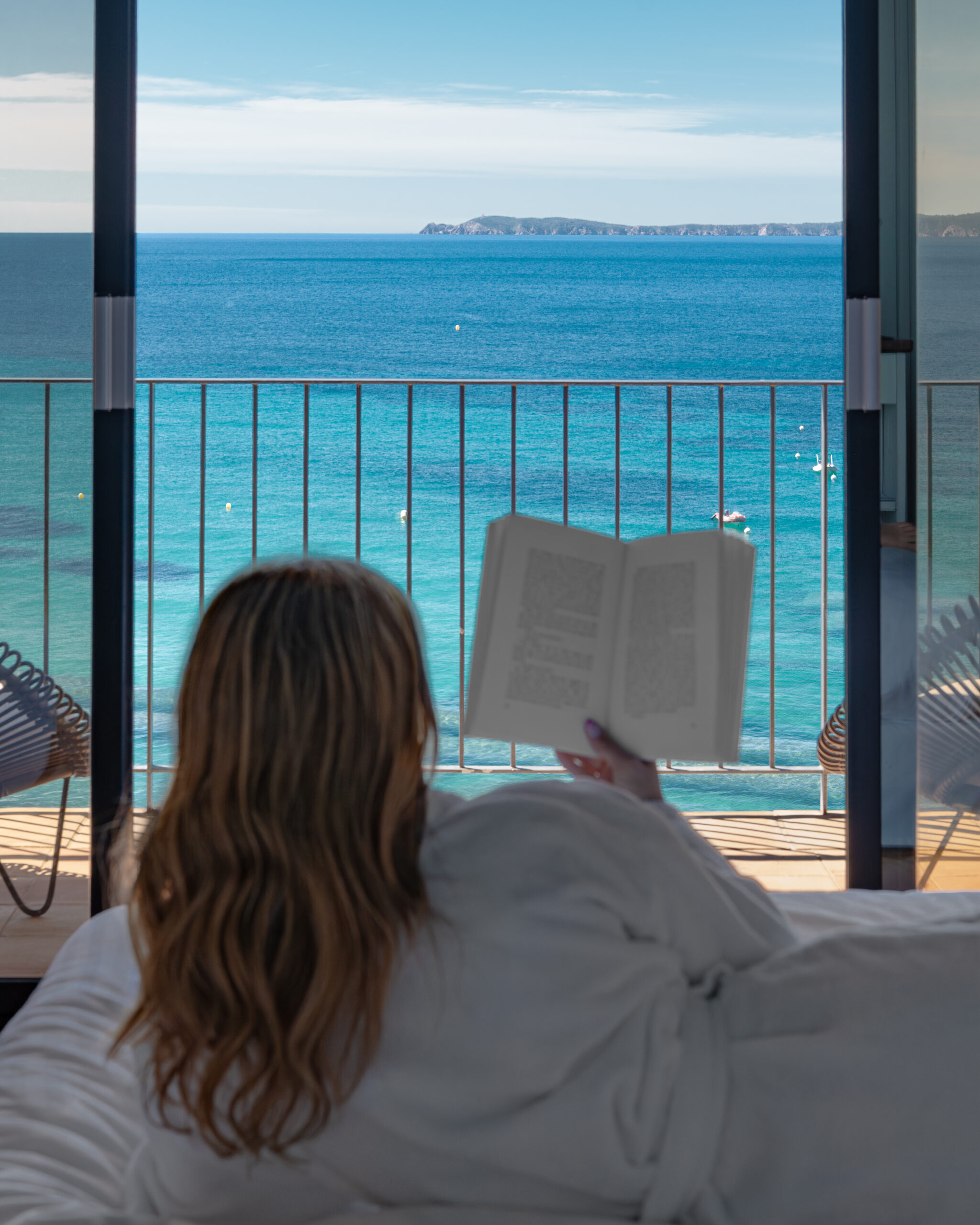 Photo lifestyle d'une jeune femme lisant un livre dans une chambre d'hôtel vue mer